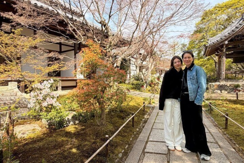 Ein traditioneller japanischer Garten mit Steinwegen, Kirschblüten und einem hölzernen Gebäude. 4