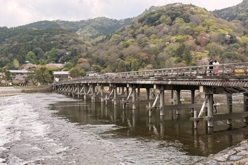 Eine Holzbrücke über einem Fluss, mit Bergen im Hintergrund. 2