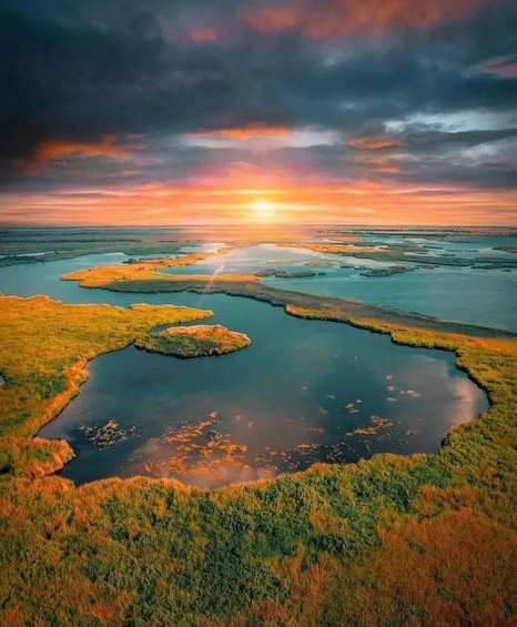 A coastal landscape with a sunset, featuring a series of water bodies and green vegetation. 3
