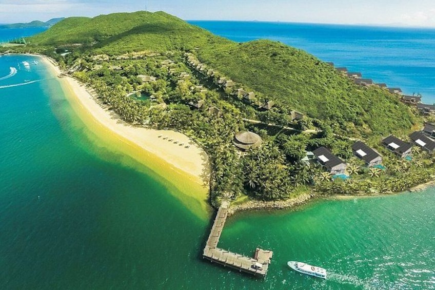 A tropical island with a beach, a dock, and several houses. 3