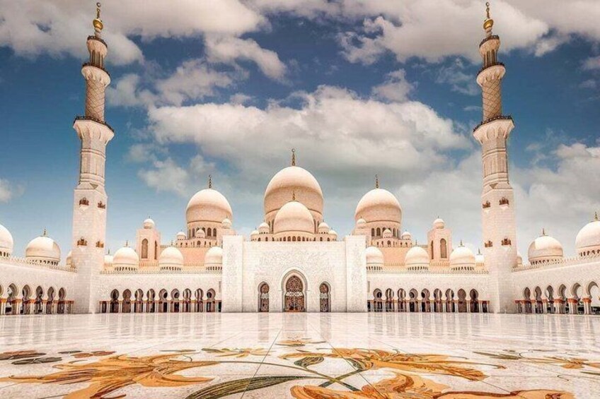 A grand mosque with multiple domes and minarets, a large courtyard, and a detailed marble floor. 1