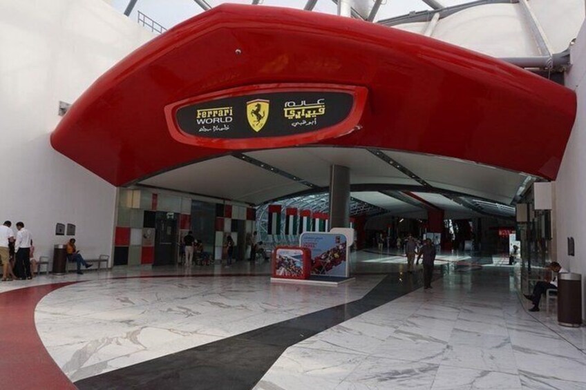 A modern indoor space with a red curved structure, a marble floor, and a digital display with logos. 5