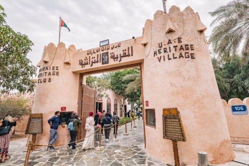 The entrance to U.A.E. Heritage Village with a stone archway and a signboard. 4