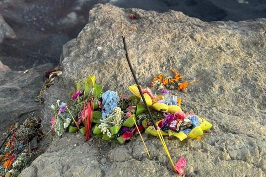 En sten dekorerad med färgstarka blommor och band. 2