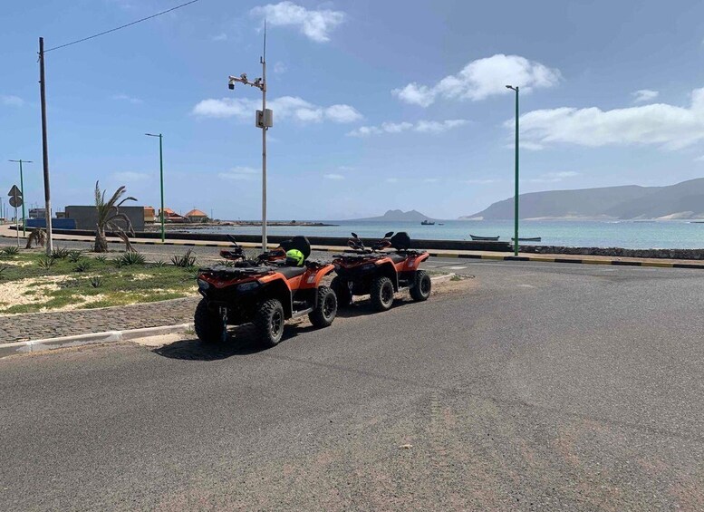 Two ATVs parked on a road with a beach and ocean in the background. 5