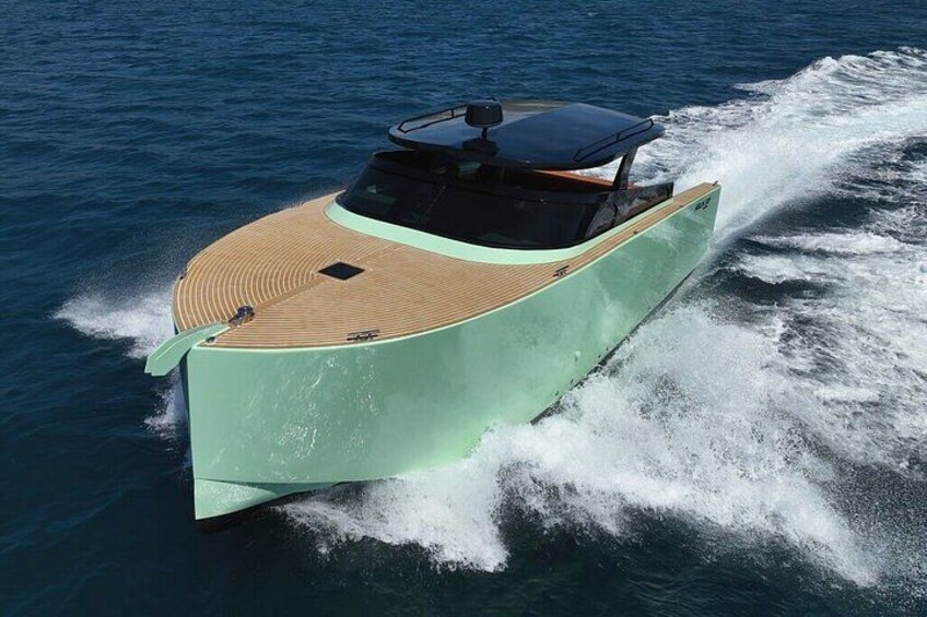 Un bateau à moteur rapide, doté d’un pont en bois et d’une coque verte, fend les eaux. 2