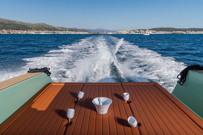 Un pont en bois sur un bateau, laissant derrière lui une vague dans l’eau, un seau blanc et une tasse blanche. 3