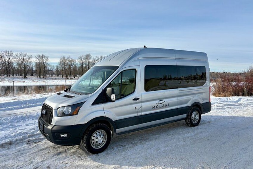 Een witte bus geparkeerd op een besneeuwde weg, met een heldere lucht. 2