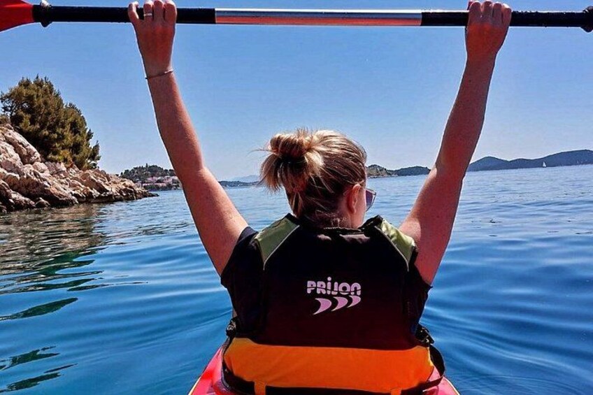 En person roer kano med en pagaj, iført redningsvest og en t-shirt med et logo. 3