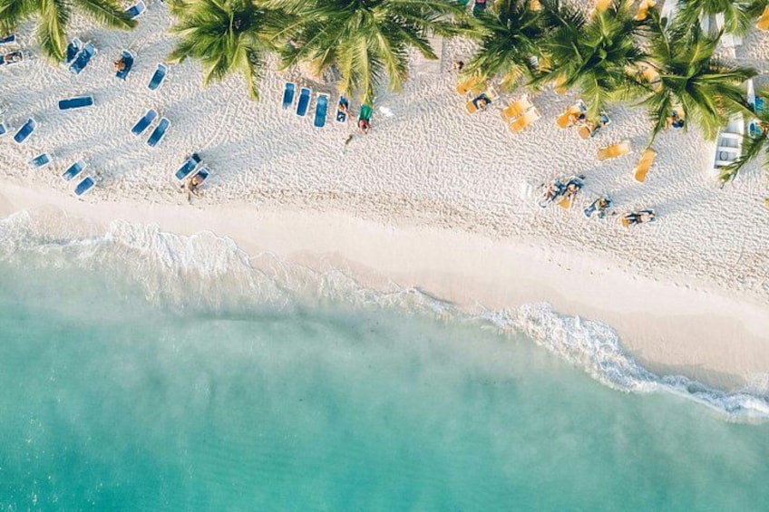 Una vista aerea di una spiaggia con sabbia bianca, acqua turchese e palme. 2