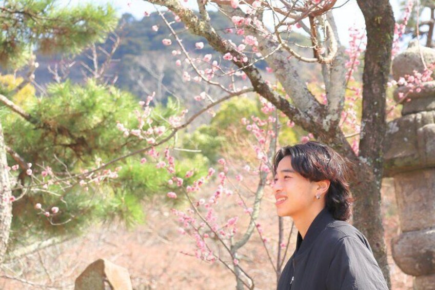 Una persona in piedi di fronte a un albero in fiore di colore rosa. 5