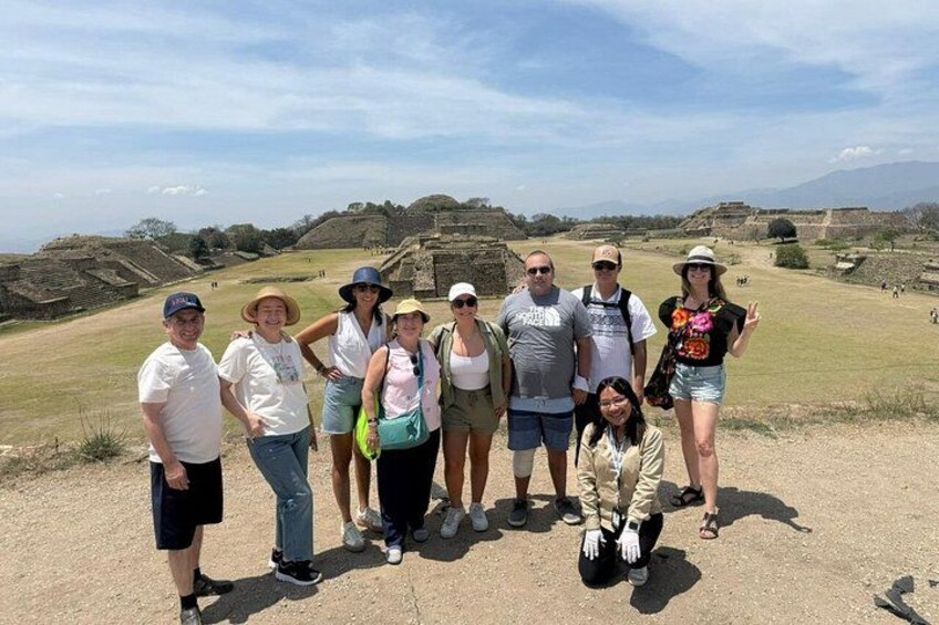 A group of people standing in front of ancient ruins with a clear sky. 5