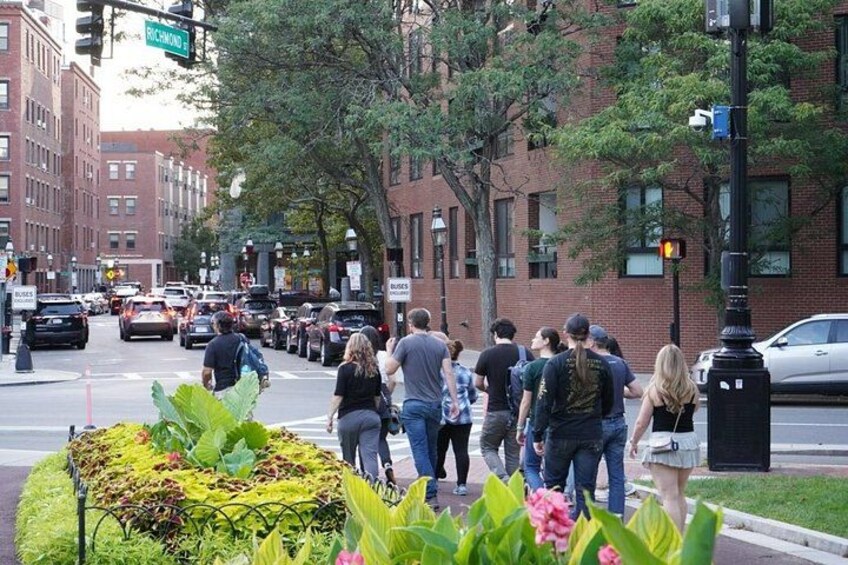 A busy street with pedestrians, cars, and buildings. 2