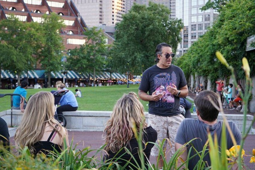 A person standing in a park with a crowd of people in the background. 3