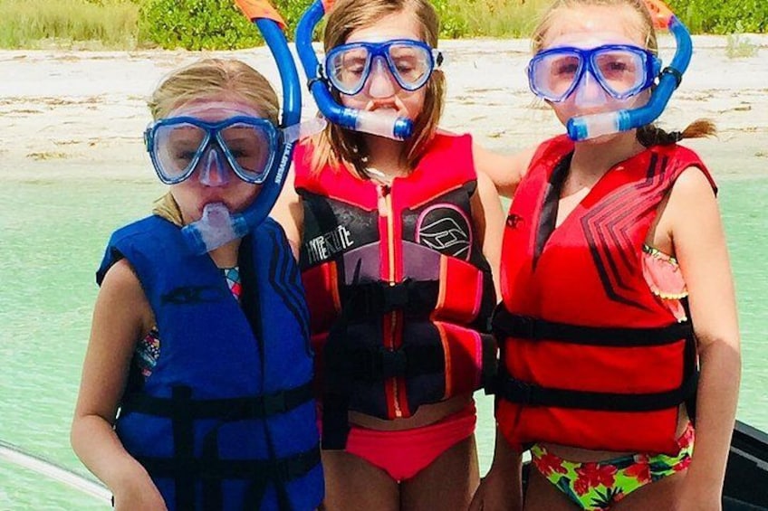 Three people wearing snorkeling gear and life vests on a boat. 5