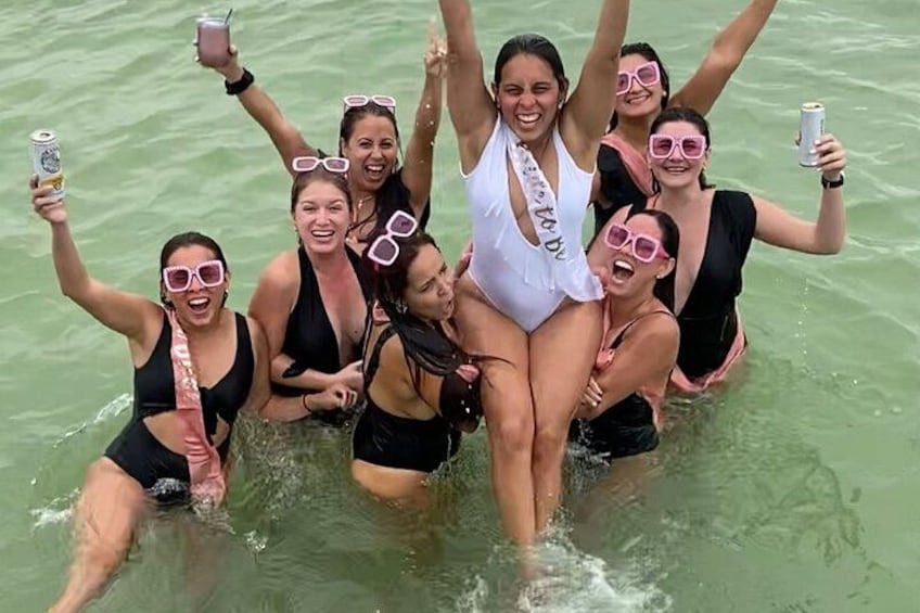 A group of people in a body of water, some wearing swimsuits and sunglasses. 4