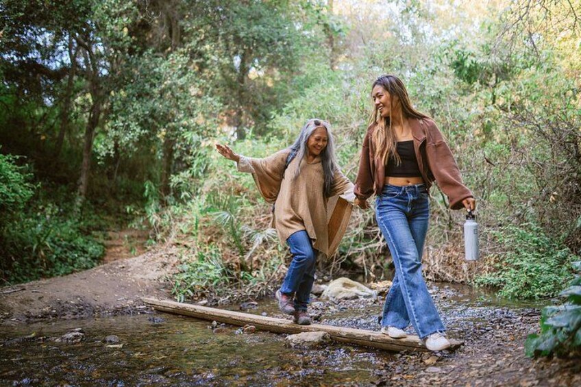 Two people walking on a forest trail, one holding a water bottle. 3