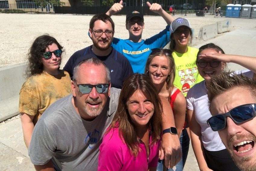 En grupp människor som poserar för ett foto på en sandstrand, med en betongbarriär i bakgrunden. 4