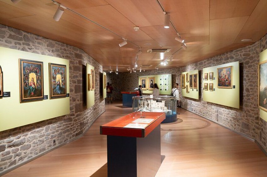 Une galerie d’art aux murs de pierre et au plancher de bois, où sont exposées diverses peintures et sculptures. 2