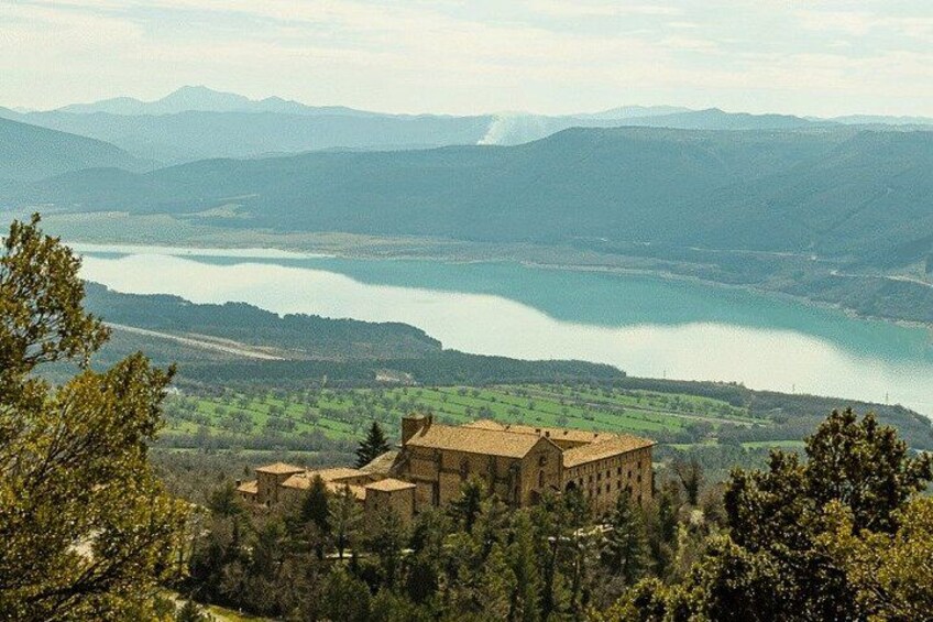 Un paysage montagneux avec un lac, un bâtiment et des arbres. 3
