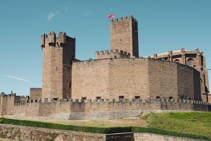 Un grand château en pierre, doté de deux tours imposantes et surmonté d’un drapeau. 1