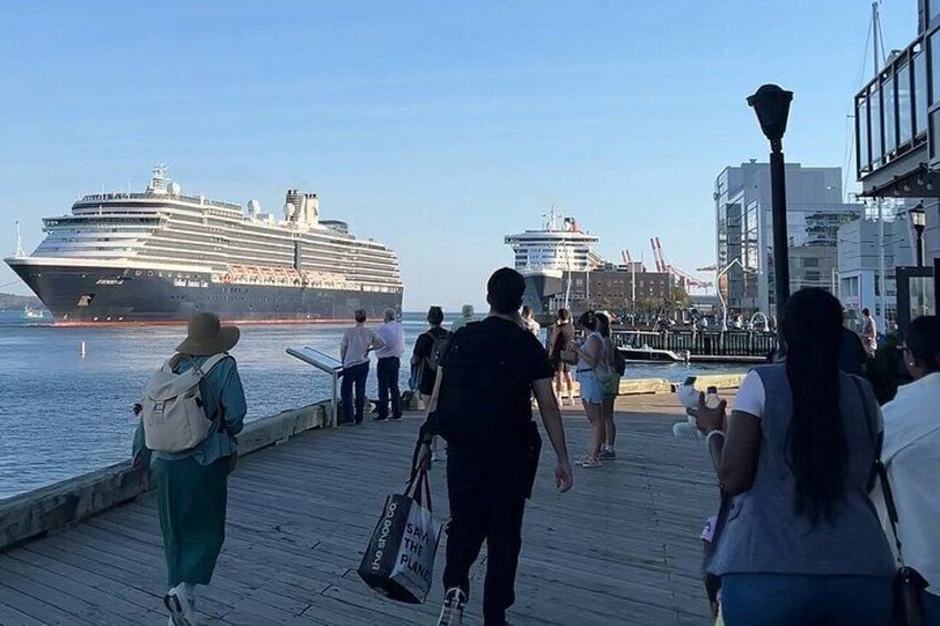 Een cruiseschip ligt aangemeerd aan een steiger, mensen wandelen erover. 4