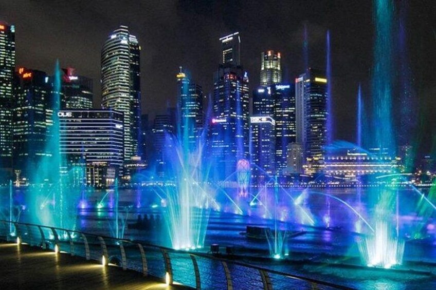 A city skyline with illuminated buildings and water fountains. 3