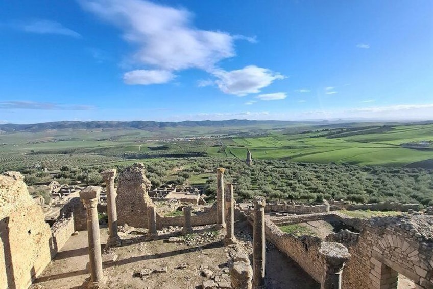 Ancient ruins with columns and a view of rolling hills and fields. 2