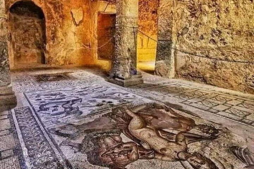 An ancient mosaic floor with intricate designs and a central figure. 5