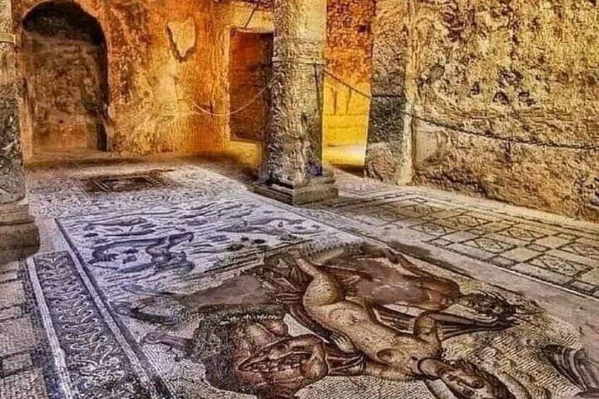 An ancient mosaic floor with intricate patterns and a stone wall. 4