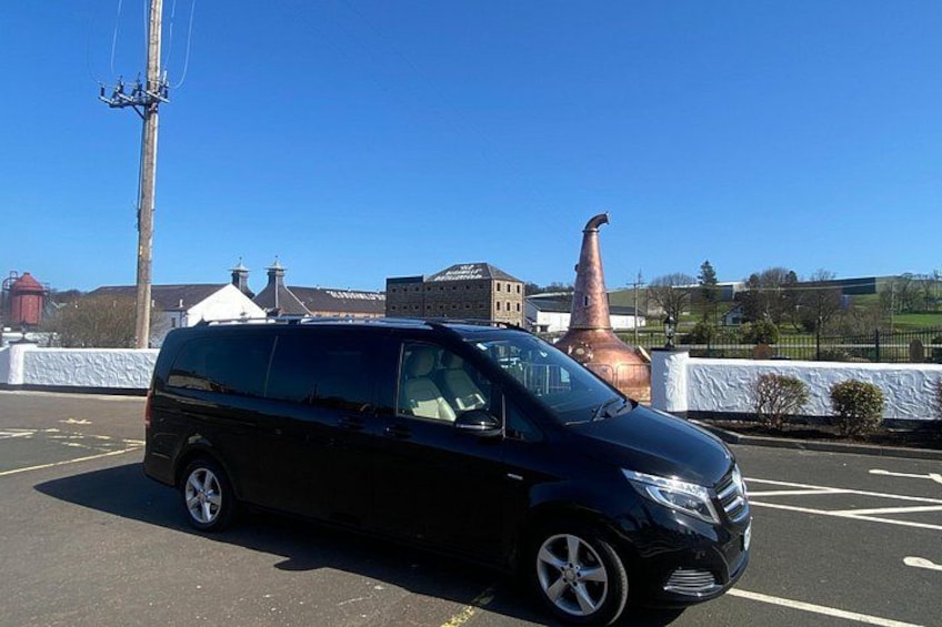 Ein schwarzer Van steht auf einem Parkplatz, im Hintergrund ein großer Kupferschornstein. 5