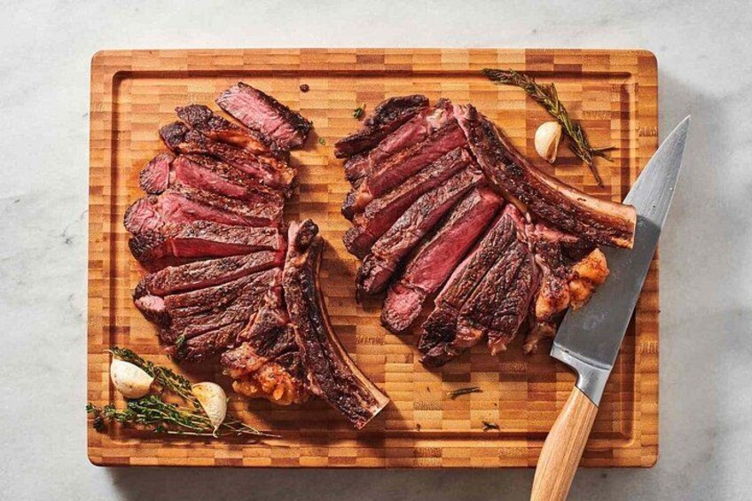 Une planche à découper en bois avec des tranches de steak, des gousses d’ail et des herbes aromatiques. 5