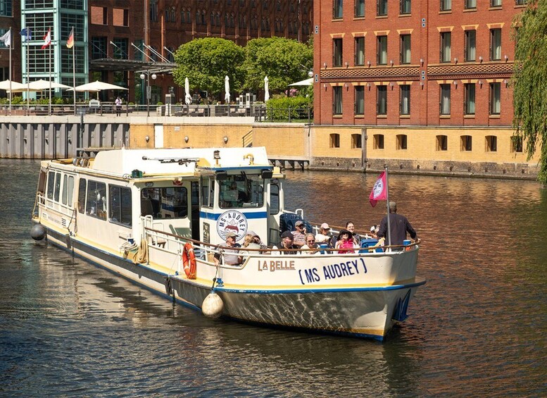 A boat named 'LABELLE' with passengers, docked near a building with a red facade. 2