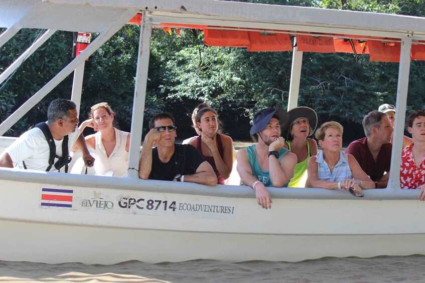 A group of people on a boat with a canopy, surrounded by greenery. 5