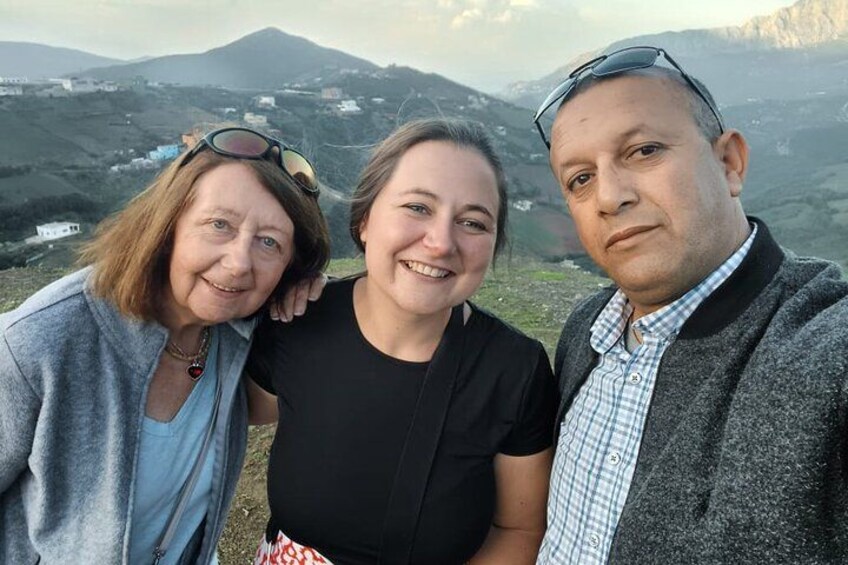 Drei Personen stehen draußen vor einer gebirgigen Landschaft. 2