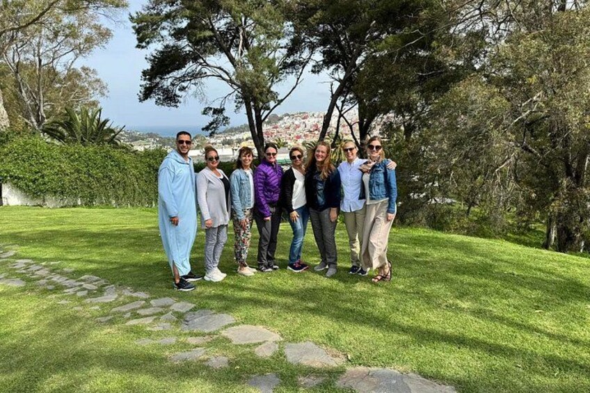 Un grupo de personas de pie en un área cubierta de césped, con árboles y un sendero de piedra al fondo. 3