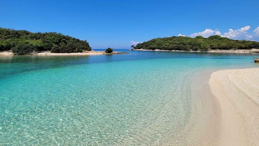 Mare turchese cristallino, spiaggia sabbiosa e colline verdeggianti. 1