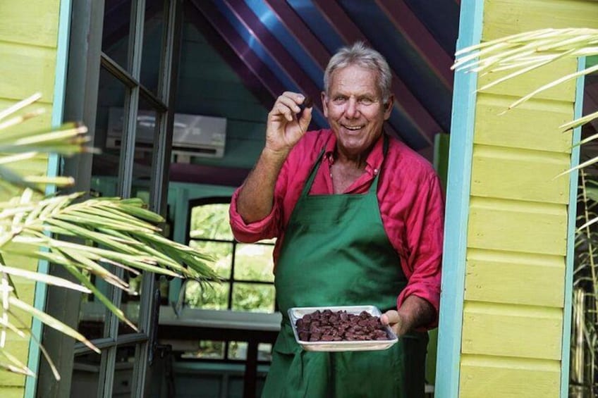 A person holding a plate of chocolate chips, standing in front of a yellow house with a green apron. 1