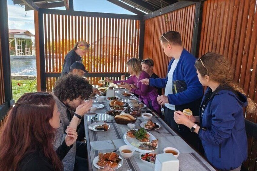 Un groupe de personnes est réuni autour d’une table en bois, à l’extérieur, et déguste différents plats. 3