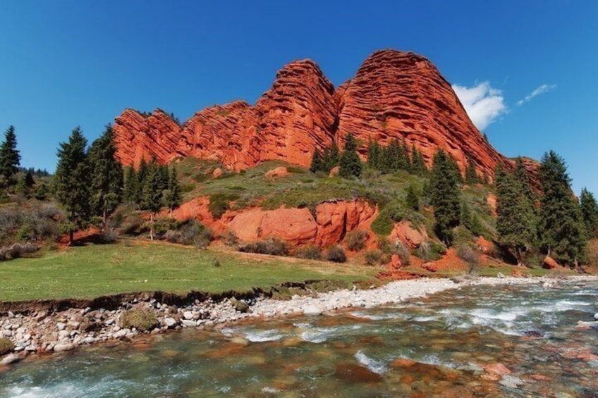 Une rivière qui traverse un paysage caractérisé par des formations rocheuses rouges et des arbres verdoyants. 1