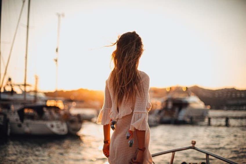 A person standing on a boat with a marina in the background. 1