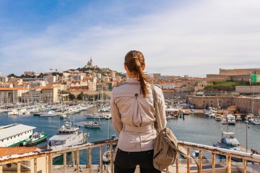 A woman overlooking a harbor with numerous boats and historic buildings. 2