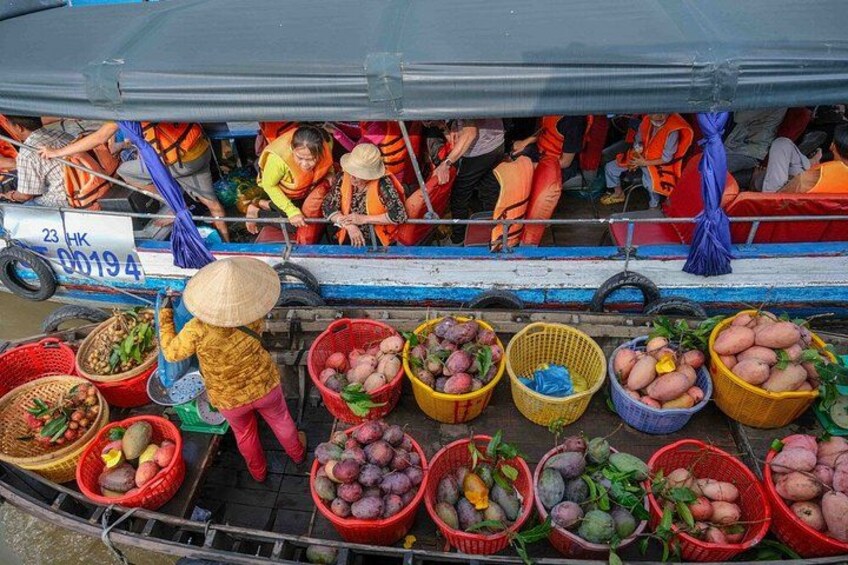 Una barca con persone che indossano giubbotti di salvataggio, cesti di frutta e un cartello con numeri. 5