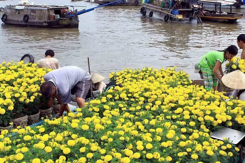 Persone che raccolgono fiori gialli lungo un fiume. 1