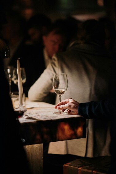 A person holding a wine glass at a dimly lit restaurant table. 1