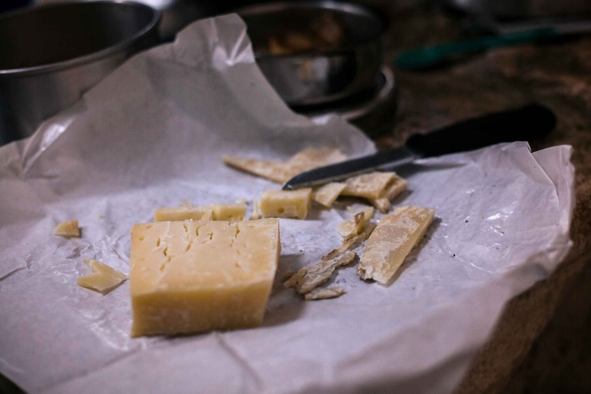 A piece of cheese on parchment paper with a knife nearby. 4