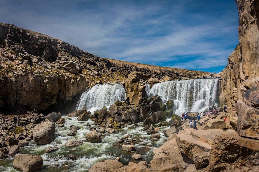 A multi-tiered waterfall with rocky terrain and a clear sky. 3