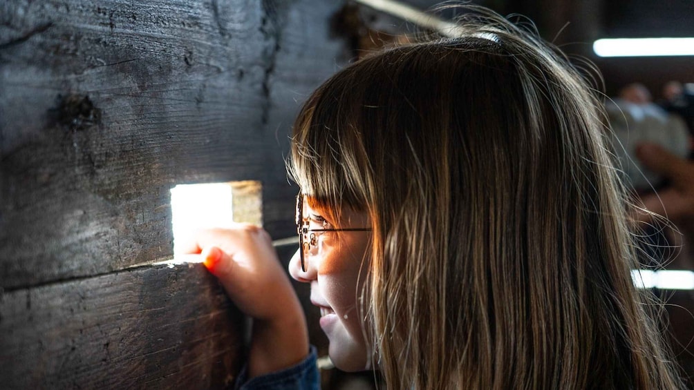 A person holding a flashlight near a wooden wall. 2