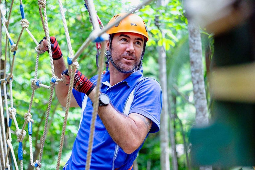 A person navigating a rope course in a forested area. 5