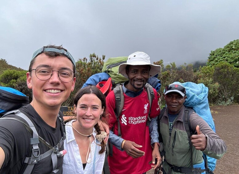 Four people hiking with backpacks in a forested area. 2
